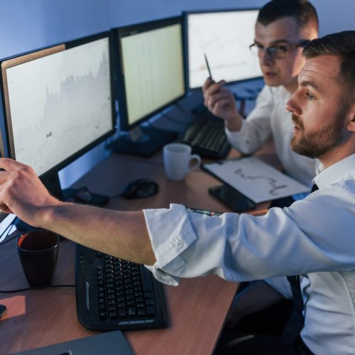 Showing graph place. Two stock traders working in the office with exchange technology Showing graph place. Two stock traders working in the office with exchange technology.